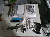 All items grouped: Wii console, balance board, power adapter, sensor bar, two remotes, nunchuk, accessory shells