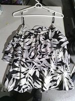 Front view of black and white ruffle spaghetti-strap blouse on hanger