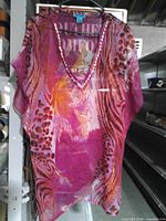 Front view of Aqua Blue sheer printed V-neck throw-over top on hanger