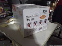 Box front showing model TS-110 meat grinder, 1200 W power rating, sealed wrap