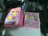Two pink Barbie carrying cases closed, showing exterior artwork