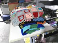 Stack of three crochet afghan blankets on table showing different patterns and colours