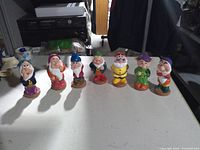 Front view of all seven dwarf squeaker figures aligned on table