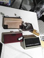 Group shot showing three wallets and one lipstick case