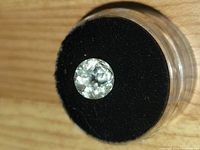 Top view of round faceted white topaz in gem jar