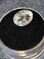 Close-up of oval faceted white topaz in gem jar
