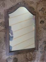 front view of mirror showing arched top, carved crest, wood frame and glass