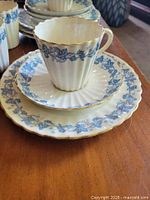 Cup, saucer and plate detail showing fluted form, blue floral border and gilt rim