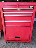 Front view of red Jobmate rolling toolbox showing four drawers, bottom cabinet door and casters