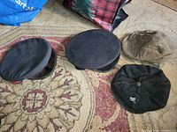 All four hats laid out: peaked cap, round cap, tweed cap, beret