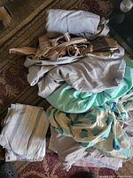 Stack of assorted queen bedding pieces in various colours and patterns