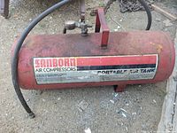 Full view of red Sanborn portable air tank with hose