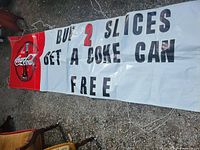 Full view of vinyl Coca-Cola banner laid out, shows text and graphics