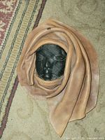 front view showing black sculpted face and tan draped cowhide