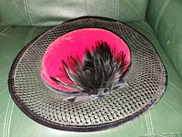 Top view showing magenta velvet crown, black feather plume, ribbon bow and mesh brim