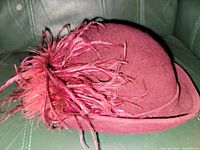 Side view of burgundy felt hat showing feather plume