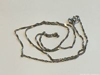 Full view of the chain coiled showing rope style and clasp