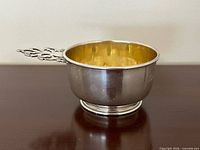 Side view showing sterling exterior, footed base, gilded interior, and handle attachment