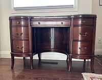 Front view of mahogany writing desk showing drawers, curved front, legs