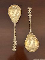 Both silver berry spoons full view showing handles and gilded bowls