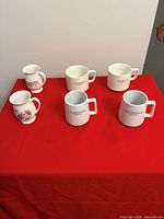 All six mugs arranged on red cloth