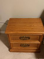Two-drawer oak nightstand, brass pulls visible