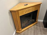 Full view of corner electric fireplace in wood mantel