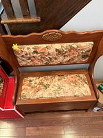 Front view of wooden deacon bench showing floral upholstery and storage seat