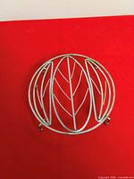 Top view of round white metal teapot holder with leaf design