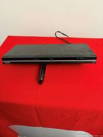 Front and top view of Toshiba DVD player on red surface, power cord visible