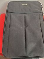 Front view of suitcase showing brand plate and front pocket