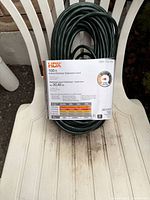 Coiled 100-ft green HDX indoor/outdoor extension cord with label showing specifications