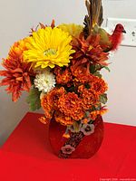 Overall view of artificial flower centerpiece in red glass vase with bird accent