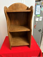 Front view of the wooden bookcase showing shelves and arched top