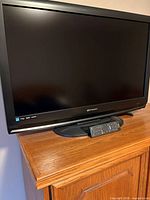 Front view of television powered off on wood cabinet