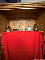 Overview of all items on wooden shelf: pair of Native American head bookends, stack of CDs, clear glass pitcher, blue and white teacup with saucer, blue mask