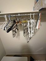 Various plastic and metal hangers hanging on rod