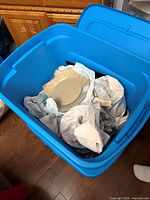 Blue plastic tote showing contents including beige plates and packing paper