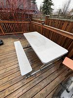 Top view of grey plastic picnic table with matching bench on wooden deck