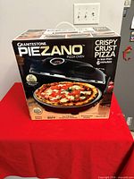 Front view of boxed Granitestone Piezano pizza oven showing branding and key features