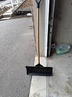 Full view of snow shovel leaning against garage wall