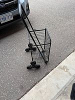 Front side view of black folding shopping cart on pavement