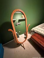 Front view of oval oak cheval mirror showing frame, stand and bedroom setting