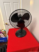 Front view of black tabletop fan on red surface