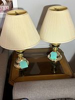 Both brass and glass table lamps with shades displayed on table