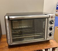 Front view showing Black+Decker branding, glass door, control knobs and interior wire rack