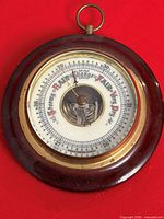 Front view of circular vintage barometer with wood case and dial