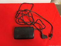 Top view of black Singer foot pedal with attached cord and plugs