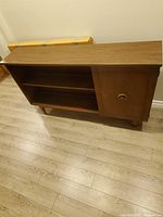 Front view of wooden shelving unit with open shelves and cabinet door