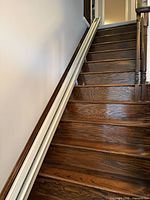 Straight cream metal rail installed on hardwood stairs